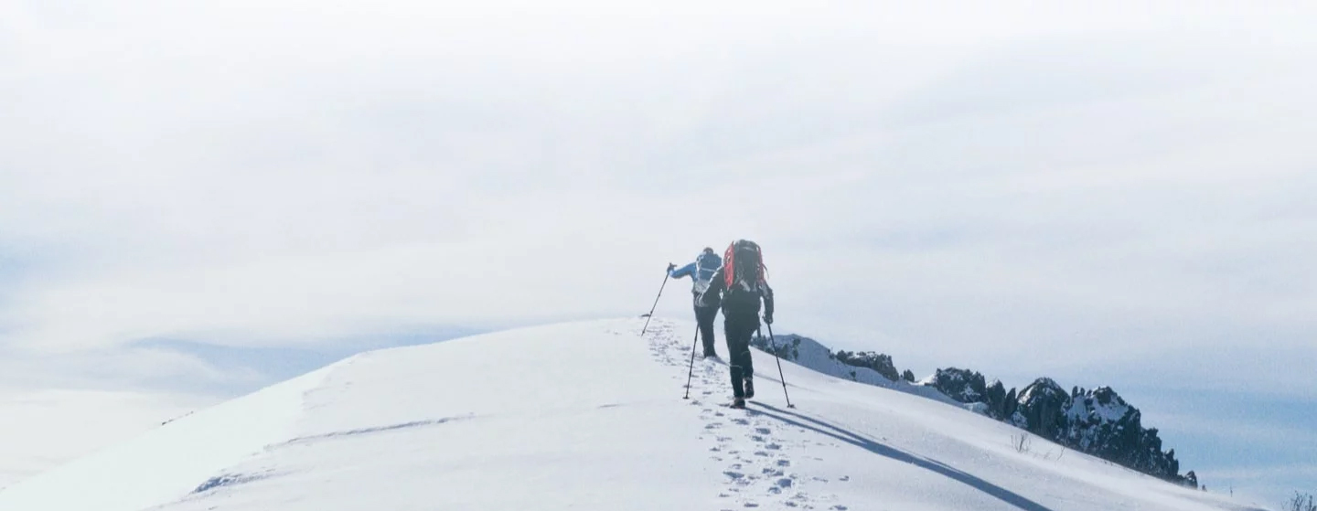 Two people hiking on a snowy mountain