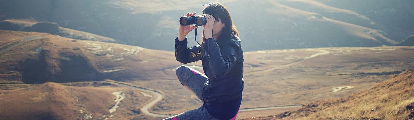 Woman on a mountain looking through binoculars